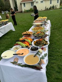 a long table filled with lots of food on top of a lush green field