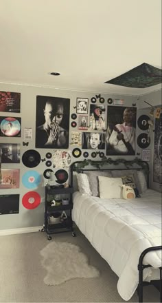 a bed sitting in a bedroom next to a wall covered with pictures and record discs