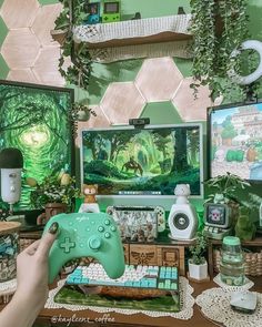 a person holding a game controller in front of a computer screen with an animated forest scene on it