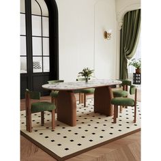 a dining room table with green chairs and a rug on the floor in front of it