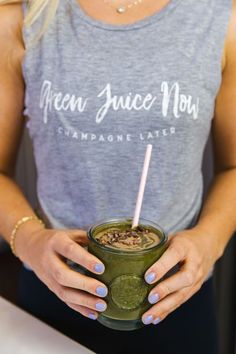 a woman holding a green smoothie in her hands