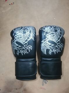 two black boxing gloves with white dragon designs on them