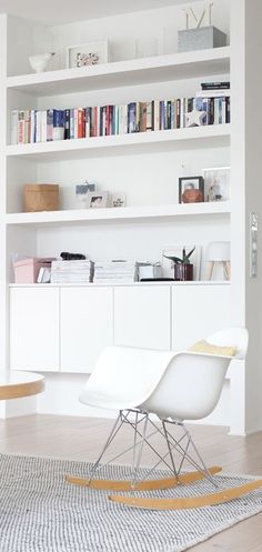 a white chair sitting in front of a book shelf