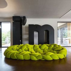 a large green bean bag chair sitting on top of a wooden floor in front of a giant m sign