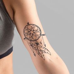 a woman's arm with a tattoo on it that has a small dream catcher