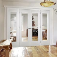 an empty room with white doors and wood flooring on the wooden floor next to a bench