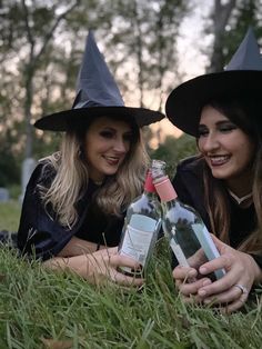 two women in witches hats pose for a photo while holding wine bottles and posing for the camera