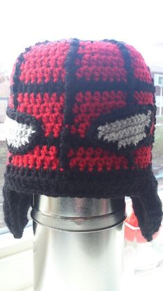 a knitted hat sitting on top of a metal trash can in front of a window