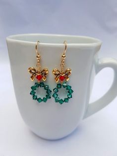 These adorable Christmas Wreath Earrings are Handmade with Emerald Green and Red Swarovski Crystal Bicone Beads and Tierra Cast, Lead-Free Pewter Bow Beads. 14K Gold Filled Ear Wire by Tierra Cast has been used. Meticulously wire wrapped with Tarnish Resistant 14k Gold Plated Wire.  Charming yet Elegant Christmas Holiday Jewelry, Holiday Jewelry With Matching Earrings, Christmas Celebration Jewelry Drop Earrings, Christmas Celebration Drop Earrings Jewelry, Holiday Dangle Earrings With Ear Wire, Festive Christmas Jewelry With Matching Earrings, Christmas Celebration Jewelry With Matching Earrings, Holiday Dangle Jewelry With Matching Earrings, Holiday Jewelry With Matching Dangle Earrings