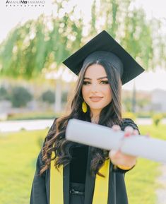 a woman wearing a graduation cap and gown holding a piece of paper in her hand