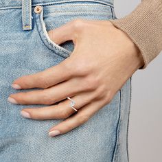 a woman's hand with a diamond ring on her left wrist, in jeans