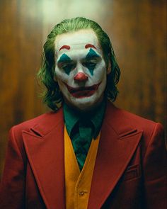 a man with green hair wearing a red suit and white face painted as the joker