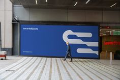 a man walking past a large blue sign in an indoor area with white and black stripes