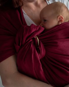 a woman holding a baby wrapped in a red wrap