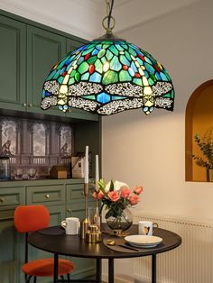 a dining room table with two chairs and a large stained glass light hanging over it