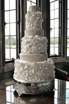 a large white wedding cake sitting on top of a table next to two window panes