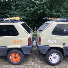 two cars parked next to each other in front of trees