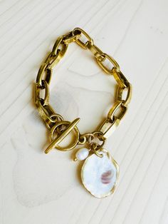 Make a statement with one of our beautiful Charleston Oyster Shell Bracelets. Chunky 12K Gold over brass chain with toggle closure and a one of a kind finished Oyster Shell and Ivory colored freshwater pearl charm. Natural oyster shell charms will range from approximately 1" to 1.5" and will vary slightly in color and shape. Two bracelet size options available, so you can choose what works best for you. Each shell has been harvested in our Charleston, SC rivers and are carefully hand finished to Shell Bracelet, Oyster Shell, Pearl Charms, Detail Shop, Charleston Sc, Brass Chain, Ivory Color, Bracelet Sizes, Charleston