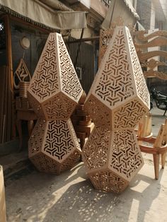 several large wooden sculptures sitting on the ground in front of a building with chairs and tables