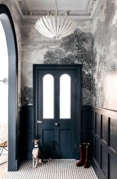 a dog sitting in front of a black door with white and gray wallpaper on it