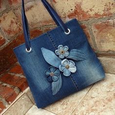 a blue purse with flowers on it sitting next to a brick wall