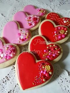 heart shaped cookies decorated with pink and red icing on a lace doily tablecloth