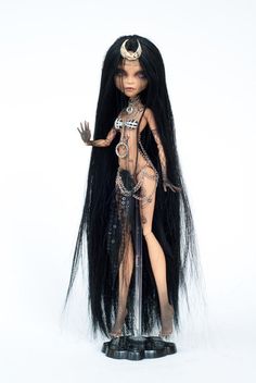 a doll with long black hair and chains on it's head, standing in front of a white background