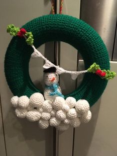 a crocheted wreath with a snowman hanging from it