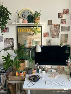 a computer desk topped with a desktop computer next to a potted plant and books