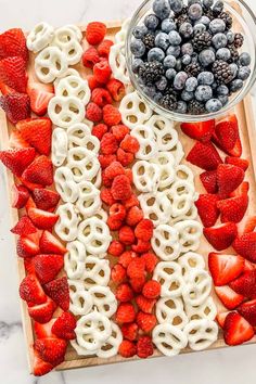 an american flag made out of pretzels, strawberries and blueberries on a cutting board