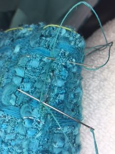 a close up view of some knitting needles on a piece of blue yarn with green thread