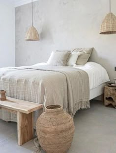 a bed sitting in a bedroom next to a wooden table and two hanging baskets on the wall