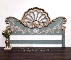 an ornate headboard sits on top of a wooden table next to a potted plant