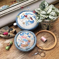 three different types of needle and thread on a wooden table next to potted plants