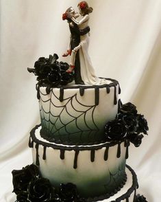 two tiered wedding cake decorated with black and white icing, roses and spider webs