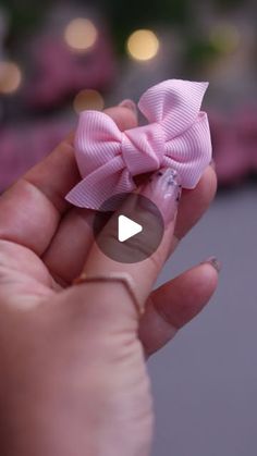 a person is holding a small pink bow in their hand with the video below it