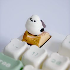 a small toy dog sitting on top of a piece of cake next to keyboard keys