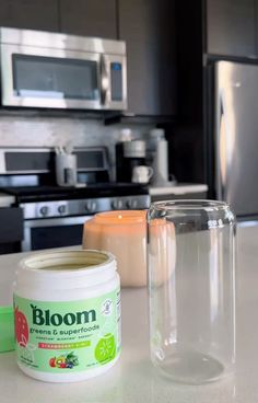 a jar of bloom sitting on top of a counter next to a container of liquid