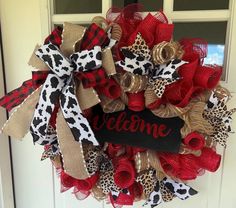 a red and black wreath with the word welcome hanging on it's front door