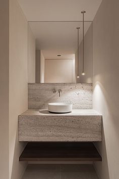 a bathroom sink sitting under a mirror next to a wall mounted faucet light