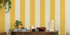 a room with yellow and white striped wallpaper, a wooden table and potted plants