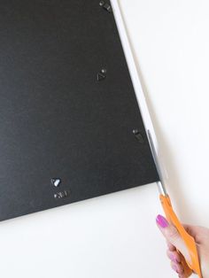 a person holding a pair of scissors in front of a piece of black paper with holes on it