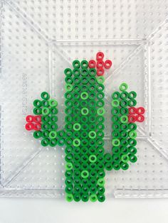 a cactus made out of plastic beads sitting on top of a white surface with holes in the middle