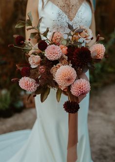 a woman in a white dress holding a bouquet of pink and red flowers on her wedding day