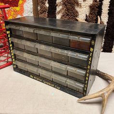 an old metal filing cabinet sitting on top of a table next to a deer's antler