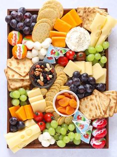 a wooden tray filled with cheese, crackers and grapes next to an orange text overlay reads how to make a cheese board for kids