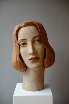 a clay head with red hair on a white pedestal