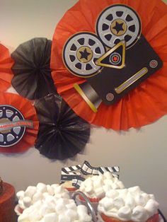 an assortment of cupcakes and desserts on display in a room with paper fans