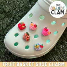 a pair of shoes with fruit and shoe charms attached to them on the grass in front of a sign that reads, the grande clam