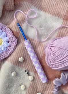 yarn, crochet hook and ball of thread on a blanket with white flowers